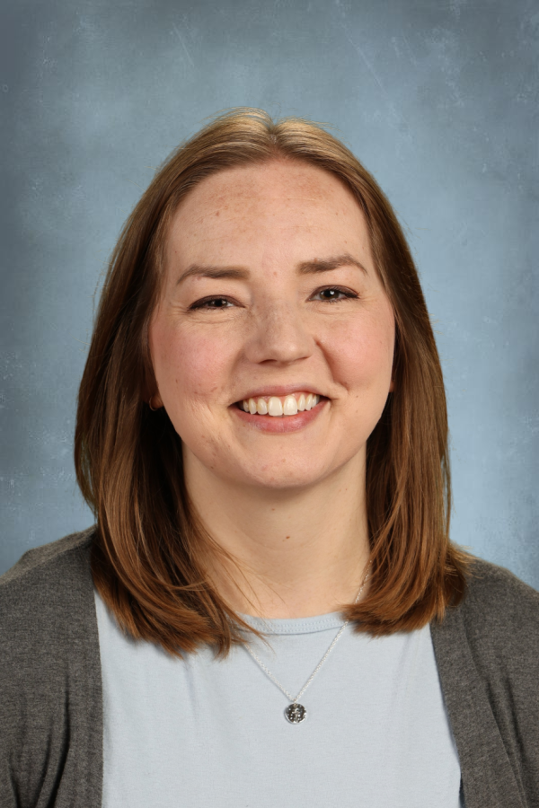 Headshot of Leah Lockett smiling, wearing a gray cardigan and a pendant necklace.