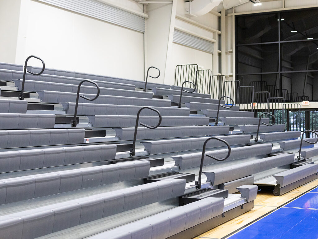 Rows of gray stadium seating with metal handrails inside a sports facility