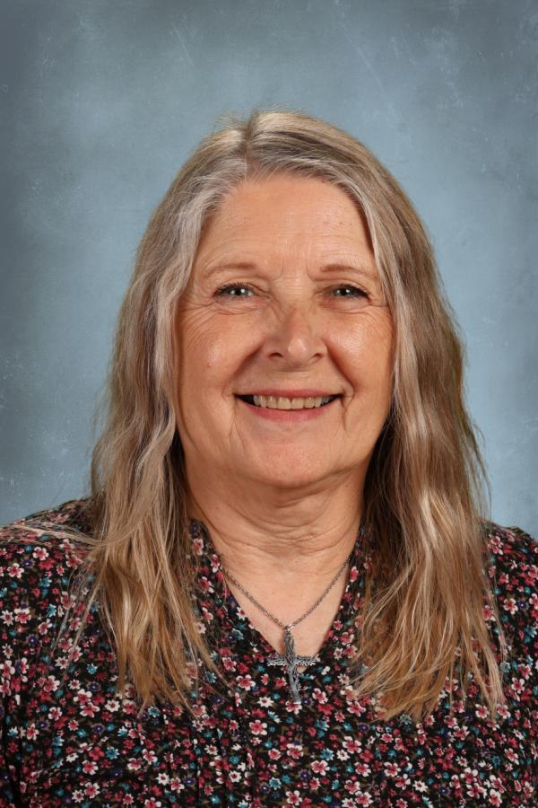 Portrait of an older woman with long blonde hair, smiling at the camera.