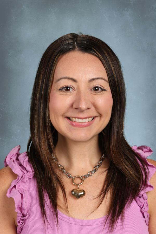 Woman with long brown hair and a heart necklace smiles.