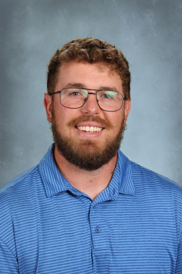 Man with beard and glasses in a blue striped polo shirt