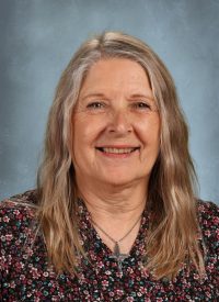 Portrait of an older woman with long blonde hair, smiling at the camera.