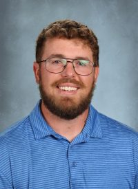 Man with beard and glasses in a blue striped polo shirt