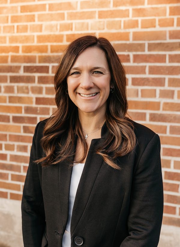 Maria Belmont smiles in front of a brick wall.